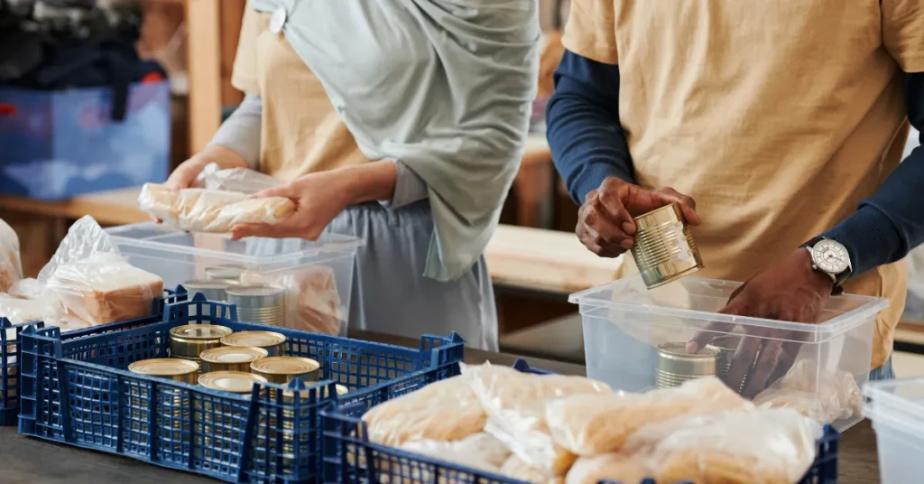 Two people standing side by side packing boxes with tinned food